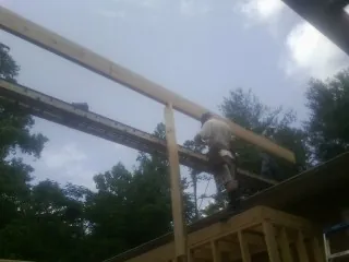 Carpenter setting a ridge beam over a new addition frame in Jacksonboro