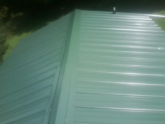 New green metal panels meeting at the ridge of a roof — Flat Roof Repair work by our crew in Jacksonboro