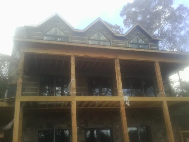 Dormers and porch framing on a large log home under construction — Roof Coating work by our crew in Jacksonboro