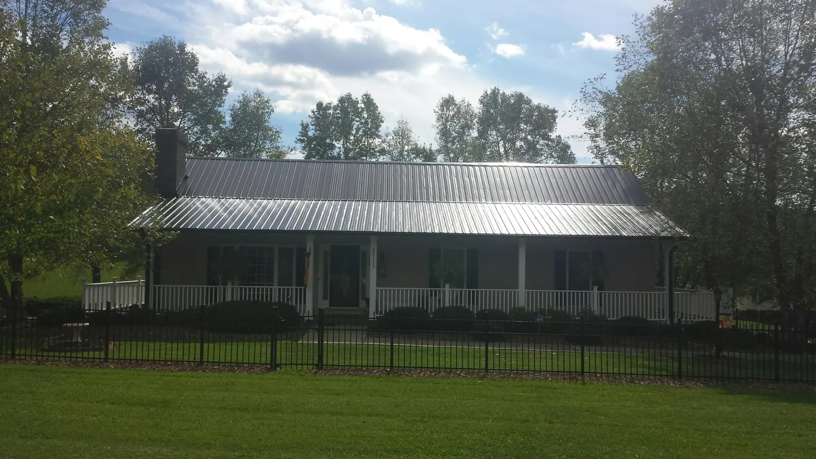 Gray metal roof on a brick ranch with a full width front porch — Gutter Guard Installation work by our crew in Jacksonboro