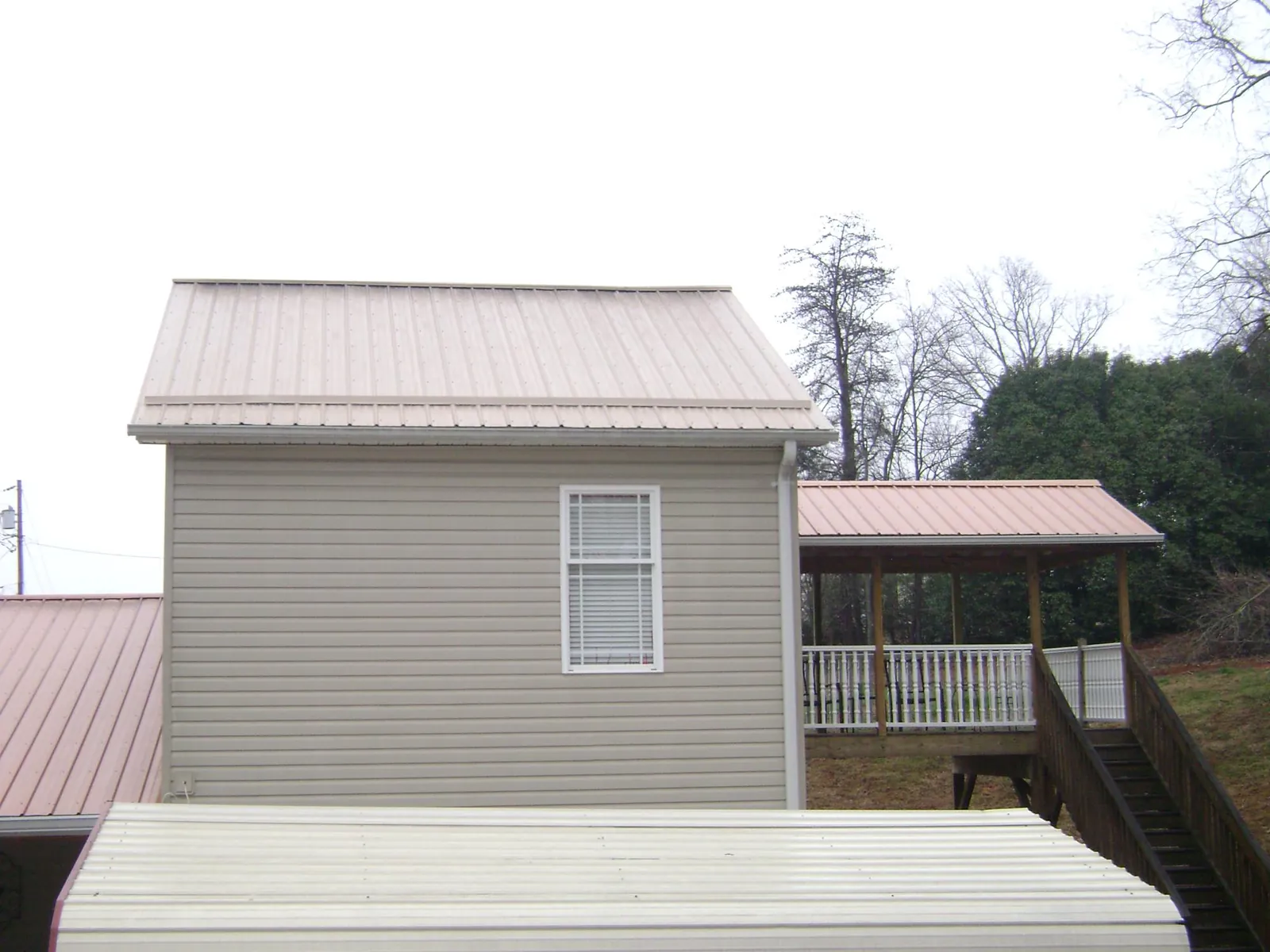 Tan metal roofs on a two story addition and attached porch, from a Roof Replacement job in Jacksonboro