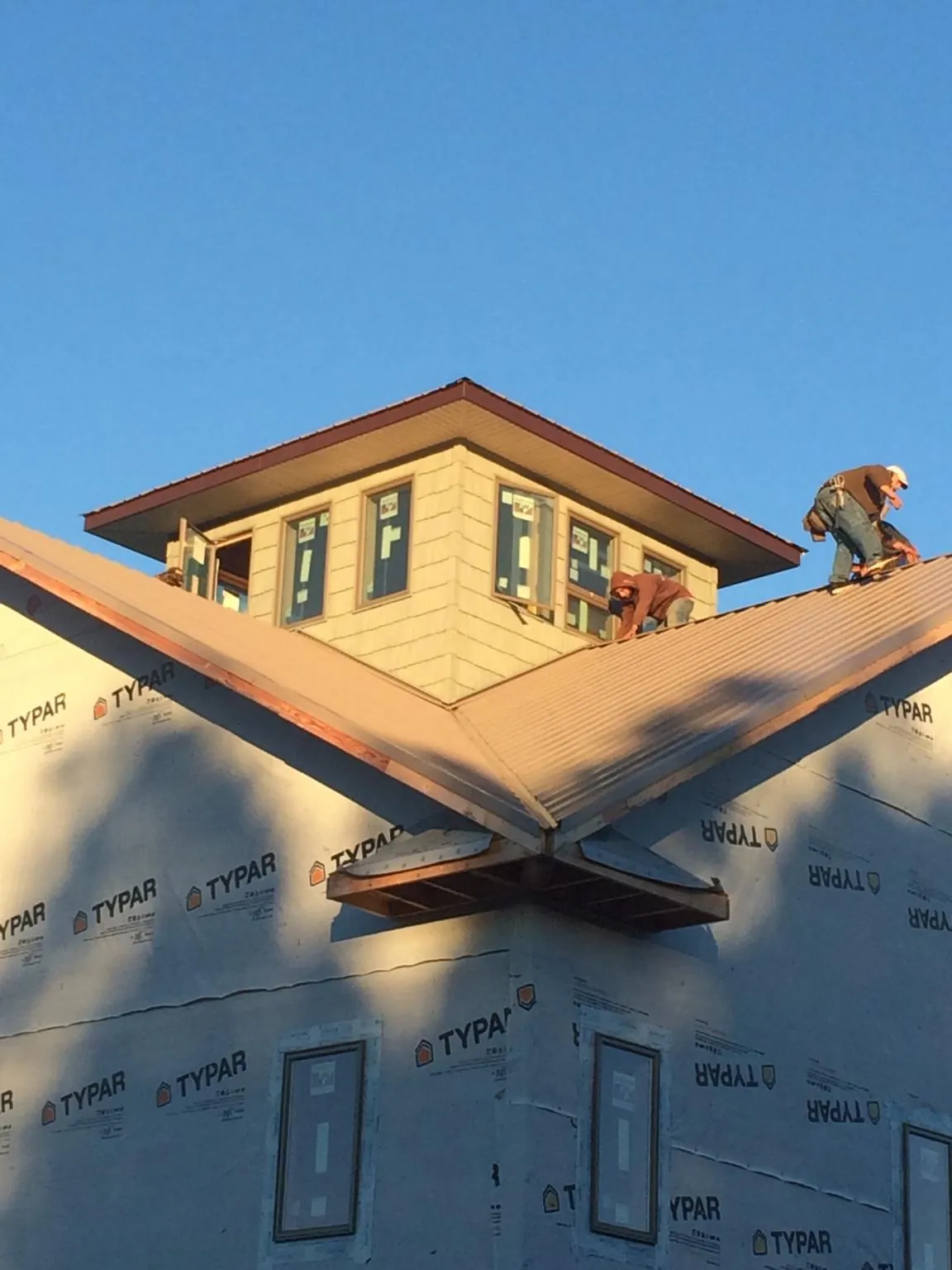 Roofers working around a rooftop cupola on a new metal roof at sunset — Roof Waterproofing in Jacksonboro by Roofing Brothers